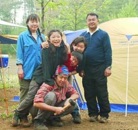 Two adults and four children pose in front of two tents