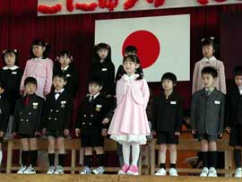 A group of young children, dressed formally, standing on a stage