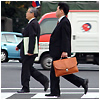Two men in suits walking in a crosswalk.