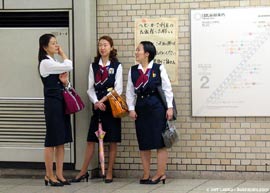 Three young women in matching outfits on train platform