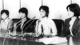 Four women at a table speak into microphones