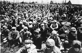 鉱山労働者たちがストライキの鉢巻をして座り込みをしています。