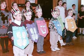 Children sing while holding signs in Hebrew.