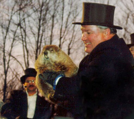 A man in a top hat holding a groundhog.
